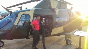 A visitor posing with an Army AW109 LOH fitted with a mini gun at LIMA 2015